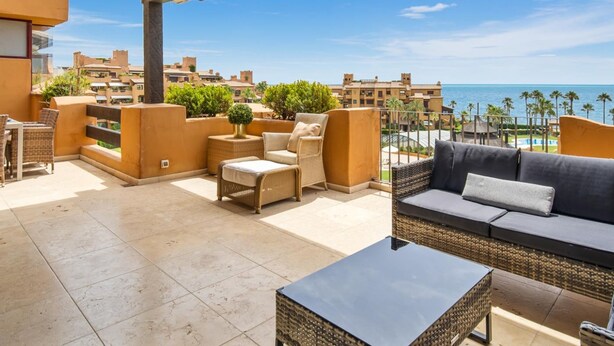A rooftop terrace with outdoor furniture, a view of the sea, and a pool area. - Apartamento Junto al mar en Estepona (Estepona)