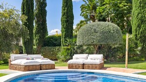 A swimming pool with two wicker lounge chairs and a neatly trimmed hedge. - Preciosa Villa con Magn Ficas Vistas en Los Flamin (Benahavis)