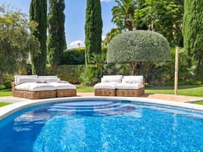 A swimming pool with two wicker lounge chairs and a neatly trimmed hedge. - Preciosa Villa con Magn Ficas Vistas en Los Flamin (Benahavis)