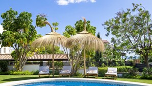 A swimming pool with lounge chairs and thatched umbrellas. - Preciosa Villa con Magn Ficas Vistas en Los Flamin (Benahavis)