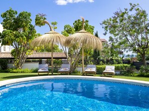 A swimming pool with lounge chairs and thatched umbrellas. - Preciosa Villa con Magn Ficas Vistas en Los Flamin (Benahavis)