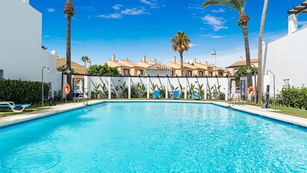A swimming pool with clear blue water, surrounded by white walls and palm trees. - Privilegio Marbella (Marbella)
