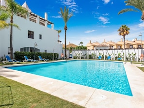 A swimming pool with lounge chairs, palm trees, and a white building with a tiled roof. - Privilegio Marbella (Marbella)