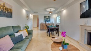 Ein modernes Wohnzimmer mit einer Couch, einem Couchtisch und einem Essbereich mit Tisch für vier Personen.