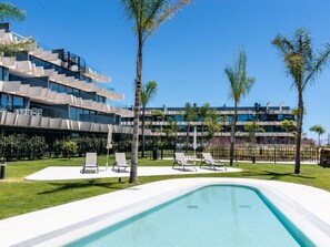Ein modernes Hotel mit Schwimmbad, Liegestühlen und Palmen.