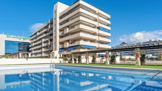 A hotel with a pool, multiple balconies, and a clear sky. - Marina Ban s c Ntrico Apartamento (Marbella)