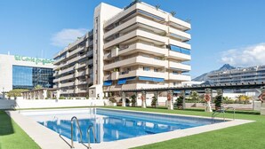A multi-story hotel with a swimming pool and a mountain view. - Marina Ban s c Ntrico Apartamento (Marbella)