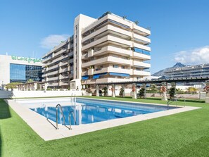 A multi-story hotel with a swimming pool and a mountain view. - Marina Ban s c Ntrico Apartamento (Marbella)