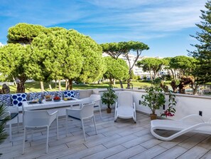 Eine Terrassengruppe mit Tisch und Stühlen, umgeben von Bäumen und Blick auf eine Wohngegend.