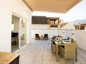 An outdoor patio with a dining table set for four, surrounded by wicker chairs. - Calle Pintado 21 Atico (Estepona)