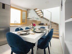 A modern kitchen with a dining area, a staircase, and a view of the outside. - Calle Pintado 21 Atico (Estepona)