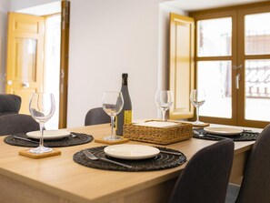Ein Esszimmertisch ist gedeckt mit Tellern, Besteck und Weingläsern, mit einer Weinflasche und einem gewebten Korb darauf.