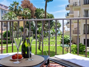 Ein Balkon mit Tisch für zwei Personen, ausgestattet mit einer Champagnerflasche, zwei Weingläsern und einem Fruchtplatten.