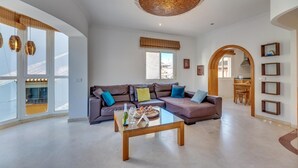 A spacious living room with a large sofa, a coffee table, and a dining area visible through an archway. - Contemporaly Huge Riyad (Estepona)