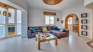 A spacious living room with a large sofa, a coffee table, and a dining area visible through an archway. - Contemporaly Huge Riyad (Estepona)