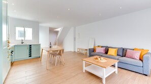 A modern living space with a dining area, kitchen, and a grey sofa with colorful cushions. - Historic Center Cozy Duplex (Estepona)