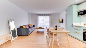 A modern apartment with a dining area, kitchen, and a living room with a sofa and a TV. - Historic Center Cozy Duplex (Estepona)