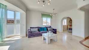 Ein geräumiges Wohnzimmer mit einer Couch, einem Couchtisch und Blick auf die Stadt durch große Fenster.