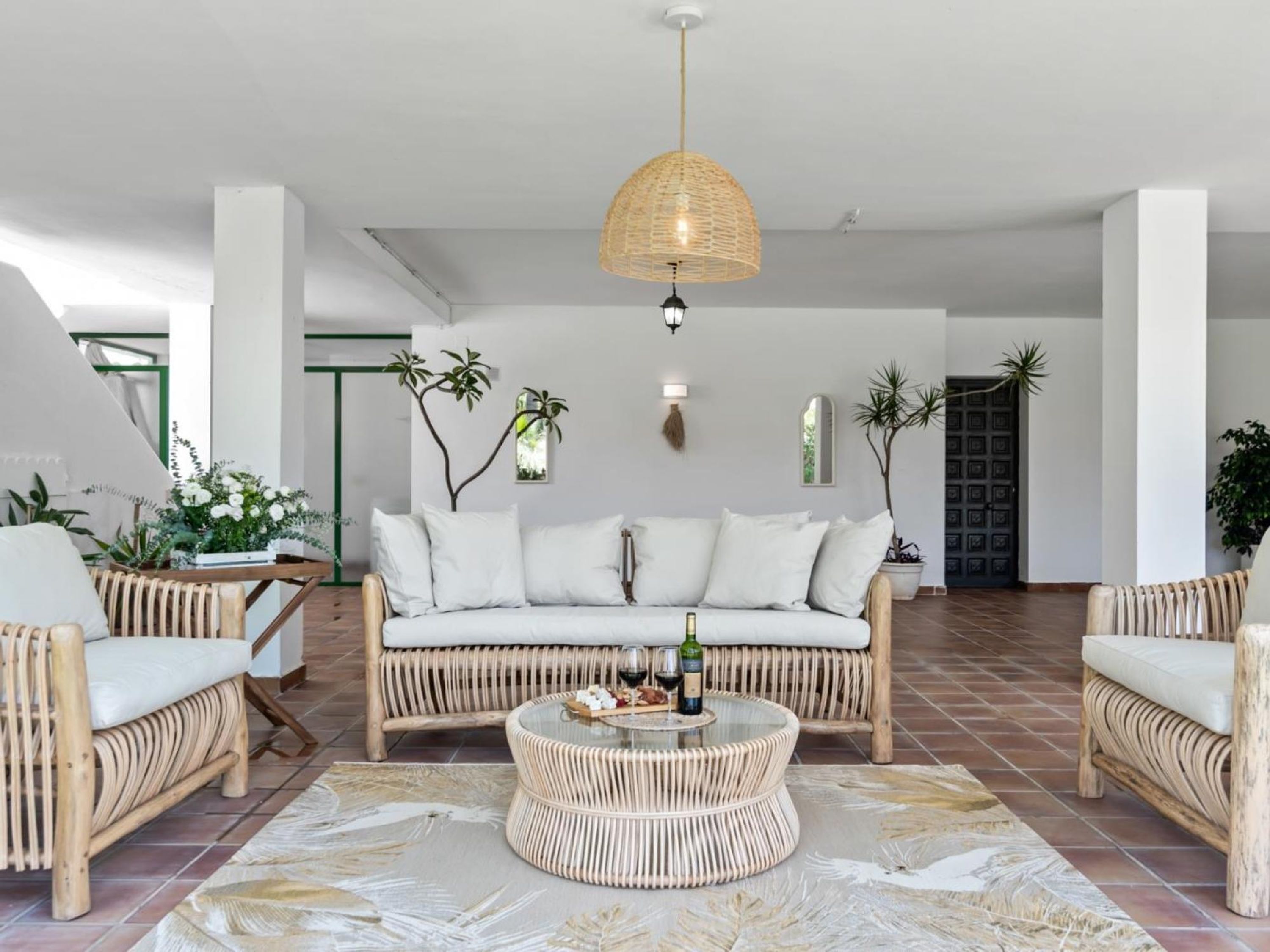 A modern living room with a sofa, two armchairs, a round coffee table, and a hanging light fixture.