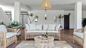 Ein modernes Wohnzimmer mit einer Couch, zwei Sesseln, einem runden Couchtisch und einer Pendelleuchte.