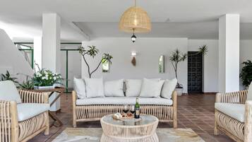 A modern living room with a sofa, two armchairs, a round coffee table, and a hanging light fixture.