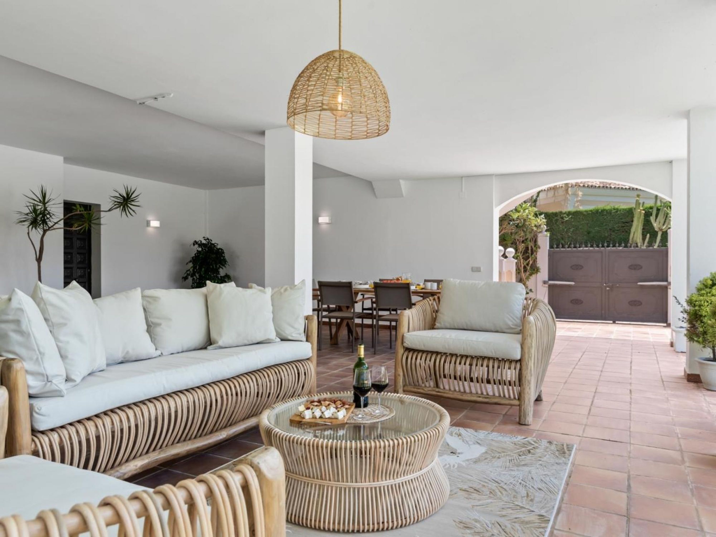 A modern living room with a sofa, chairs, a round table, and a hanging light fixture.