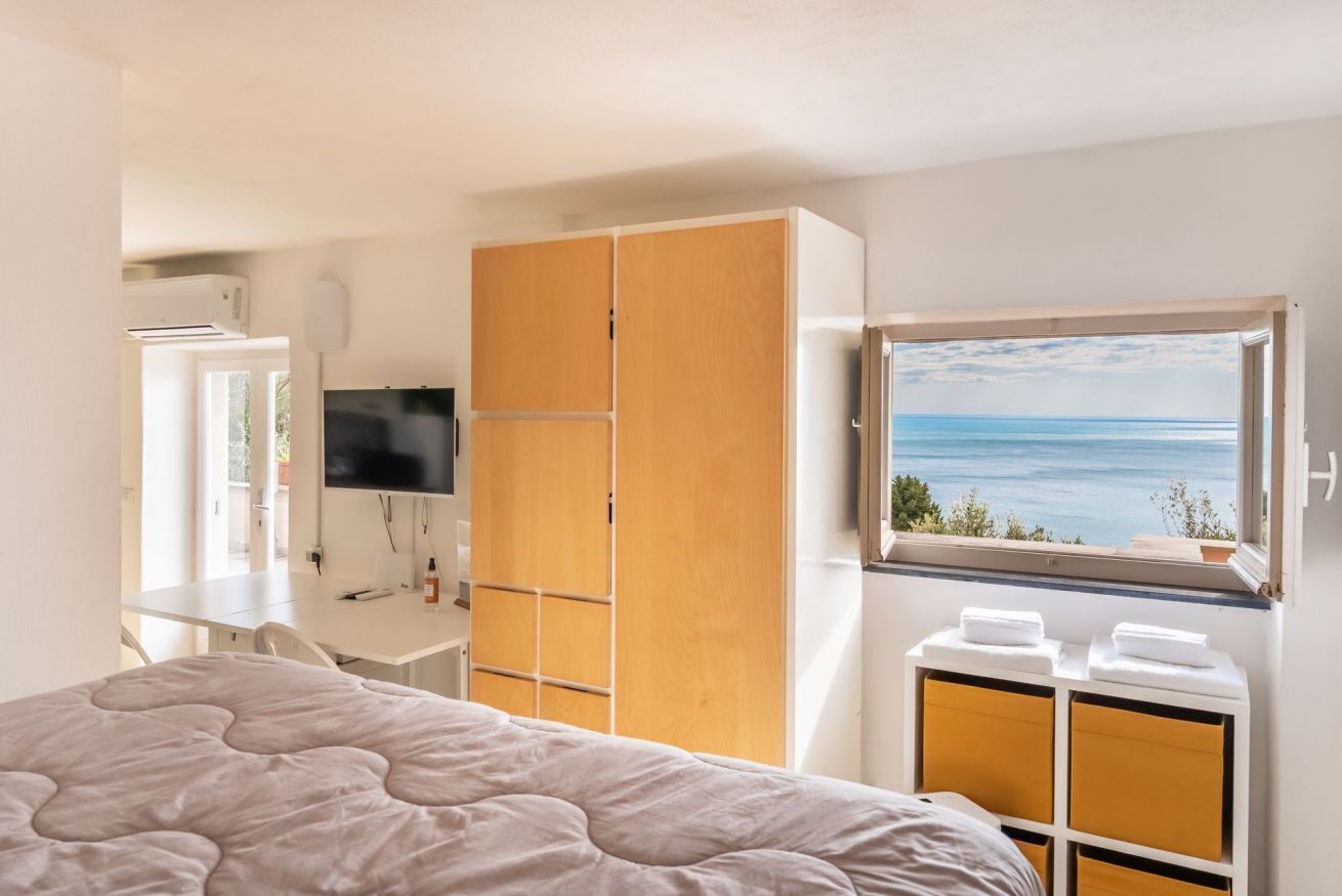 Une chambre à coucher avec un lit, une télévision, une armoire et une fenêtre donnant sur un beau paysage.