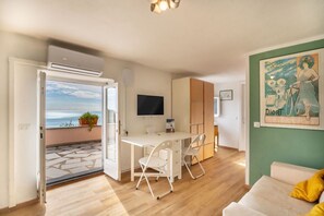 A modern living space with a dining area, a flat-screen TV, and a view of the sea through an open door. - [Terrazzasulmare] privateparking-seaview-A/C (Tellaro)