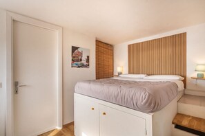 Ein Schlafzimmer mit einem Bett, einem Holzkopfende, einem Nachttisch mit Lampe und einer Tür.