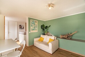 Ein Zimmer mit einem weißen Sofa, einem Esstisch und einer grünen Wand.