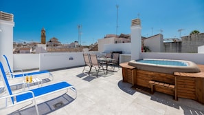 Eine Dachterrasse mit Whirlpool, Liegestühlen und einem Esstisch.