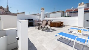 Eine Dachterrasse mit Grillplatz, Sitzgelegenheiten und einem Billardtisch.