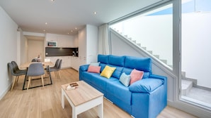 Una sala moderna con un sofá azul, una mesa de comedor y una zona de cocina.