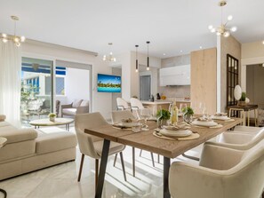 A modern dining area with a wooden table set for a meal, surrounded by comfortable seating. - 3 Dormitorios en Playas del Duque Ref C2 111 (Marbella)