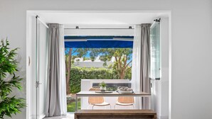 Ein Zimmer mit einem Holztisch und -stühlen, einer Bank und Blick auf einen Garten durch eine Glastür.