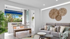 Ein modernes Wohnzimmer mit grauem Sofa, einem Couchtisch und einem Essbereich mit Tisch und Stühlen.