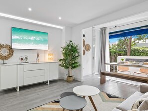 Ein moderner Wohnraum mit Küche, Essbereich und großem Fenster mit Blick auf einen Garten.