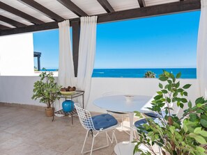 A terrace with a table and chairs, a potted plant, and a view of the sea. - Br Playas Del Duque Ref C412 (Marbella)