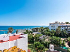 A coastal hotel with a view of the sea, a garden with various plants, and a white building with balconies. - Br Playas Del Duque Ref C412 (Marbella)