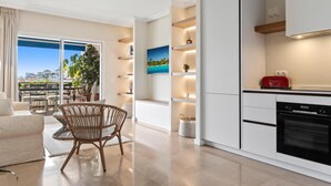 Eine moderne Küche mit Backofen, ein Essbereich mit Korbsessel und Meerblick durch große Fenster.
