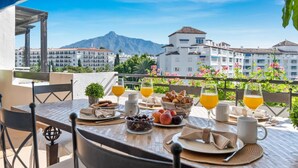 Ein Tisch ist für das Frühstück gedeckt, mit Blick auf Gebäude und Berge.