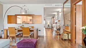 A modern living room with a dining area, a purple ottoman, and a hallway leading to a bedroom. - 03 Dormitorios ref Casa Granada 146 (Marbella)