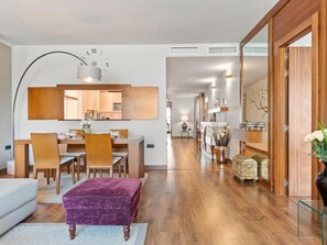 A modern living room with a dining area, a purple ottoman, and a hallway leading to a bedroom. - 03 Dormitorios ref Casa Granada 146 (Marbella)