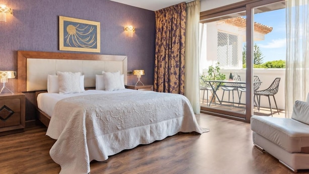 A hotel room with a large bed, a view of the outdoor patio, and a painting on the wall. - 03 Dormitorios ref Casa Granada 146 (Marbella)