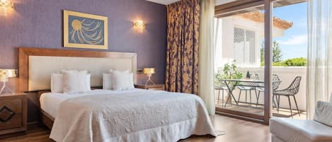 A hotel room with a large bed, a view of the outdoor patio, and a painting on the wall.
