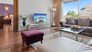 A modern living room with a large window, a flat-screen TV, a sofa, a coffee table, and a small side table with a lamp. - 03 Dormitorios ref Casa Granada 146 (Marbella)