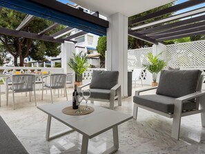Ein Terrassenbereich im Freien mit Tisch, zwei Stühlen und einer Weinflasche.