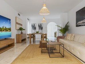 Ein modernes Wohnzimmer mit Flachbildfernseher, einer Couch, einem Couchtisch und einem Essbereich.