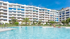 Un hotel con una grande piscina, numerosi balconi e un cielo azzurro.