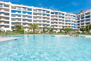 A hotel with a large swimming pool, multiple balconies, and a clear blue sky. - Confortable y c Ntrico en Terrazas de Ban s (Marbella)